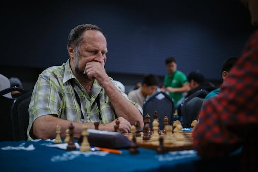 Senior man deeply focused playing chess in a tournament environment.