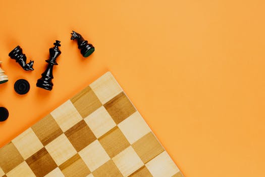 Flat lay of scattered chess pieces and board on a vibrant yellow background, symbolizing strategy and challenge.