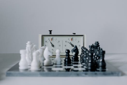 Close-up view of a chess match featuring black and white pieces and a chess clock.