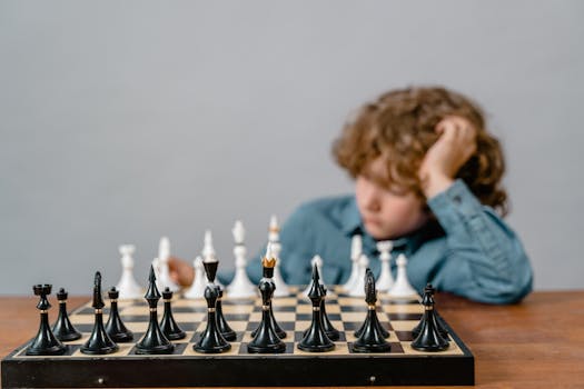 A young boy concentrates on a chess game, highlighting the strategic intensity of learning and playing chess.